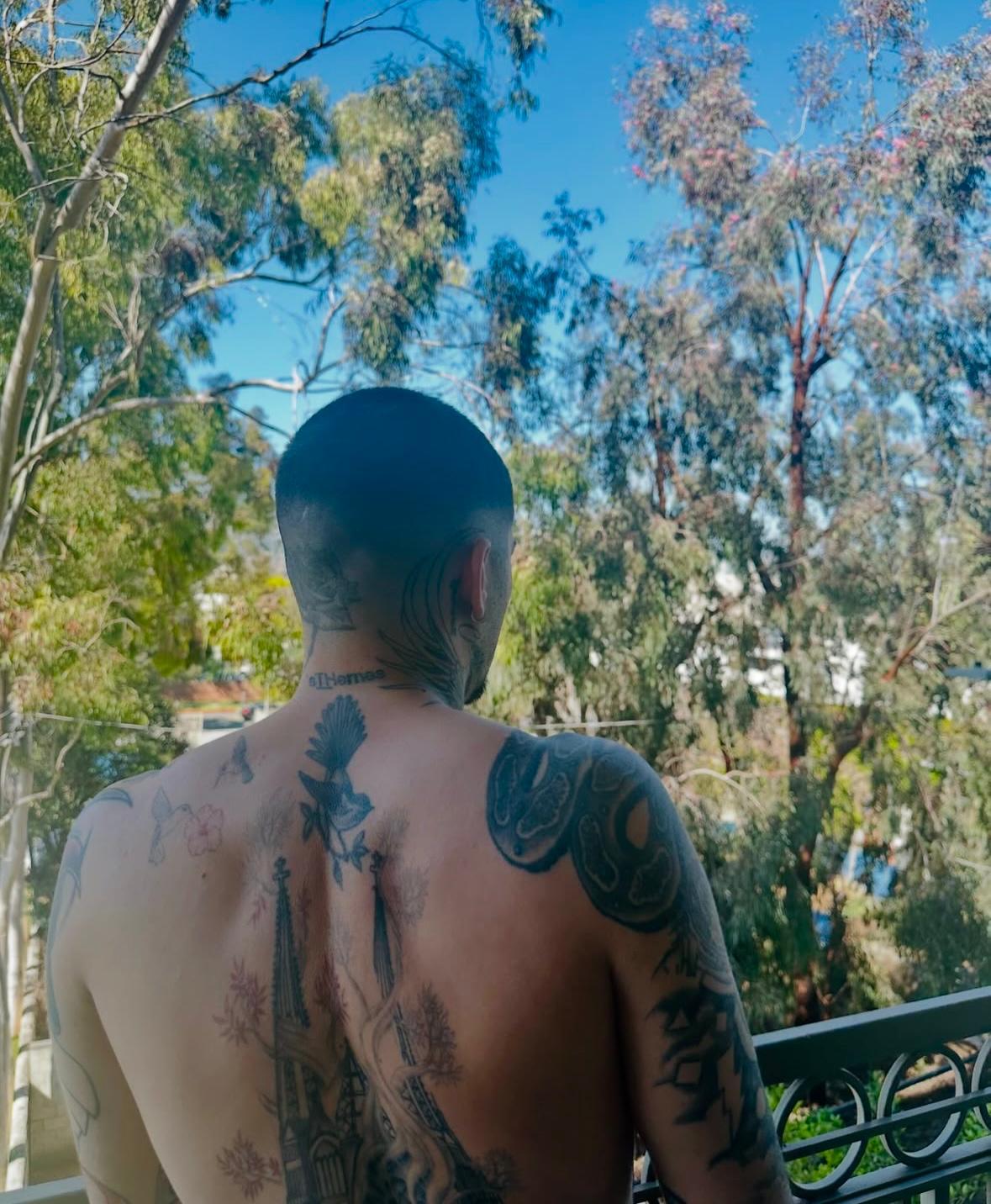 A person with tattoos on his back

Description automatically generated