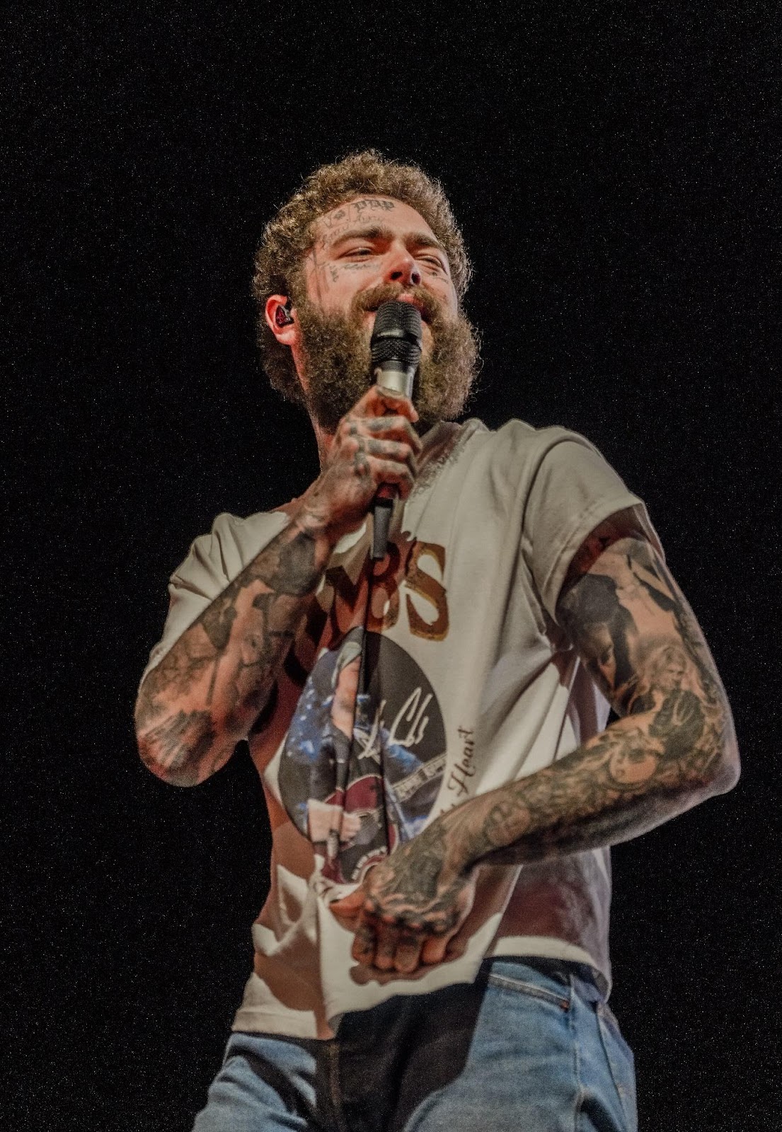 A person with tattoos holding a microphone

AI-generated content may be incorrect.